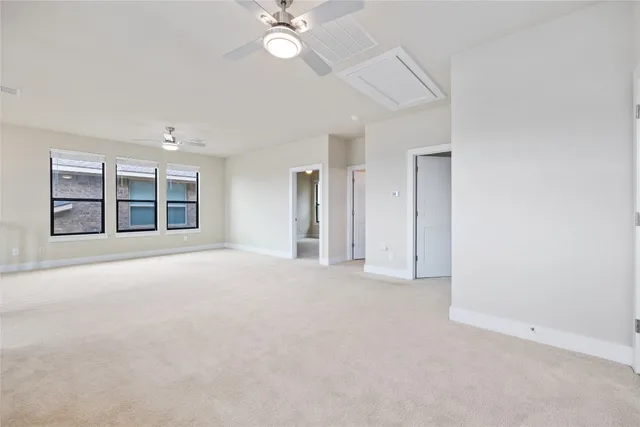 an empty room with chandelier fan and windows