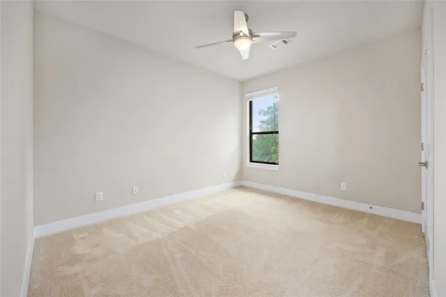 an empty room with a window and a ceiling fan