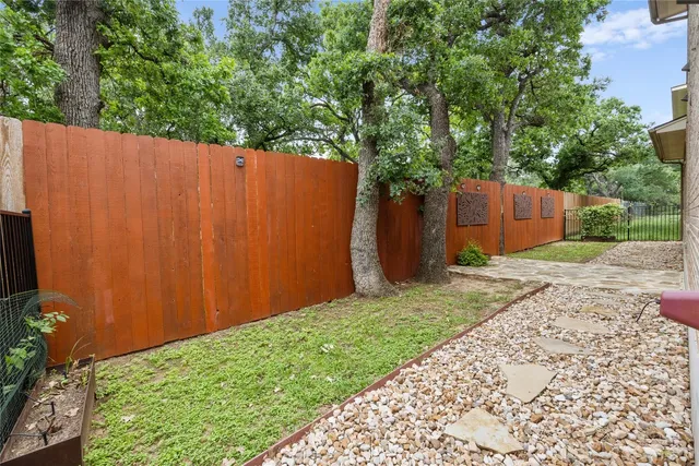a view of a backyard with potted plants and large tree