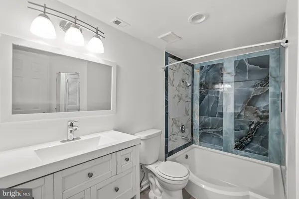 a bathroom with a bathtub shower sink vanity mirror and toilet