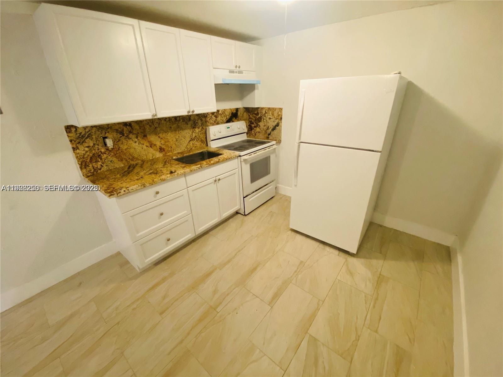 2230 Northwest 51st Terrace, Unit 2 Miami, FL 33142 - Photo 3 of 10 a kitchen with cabinets and a refrigerator