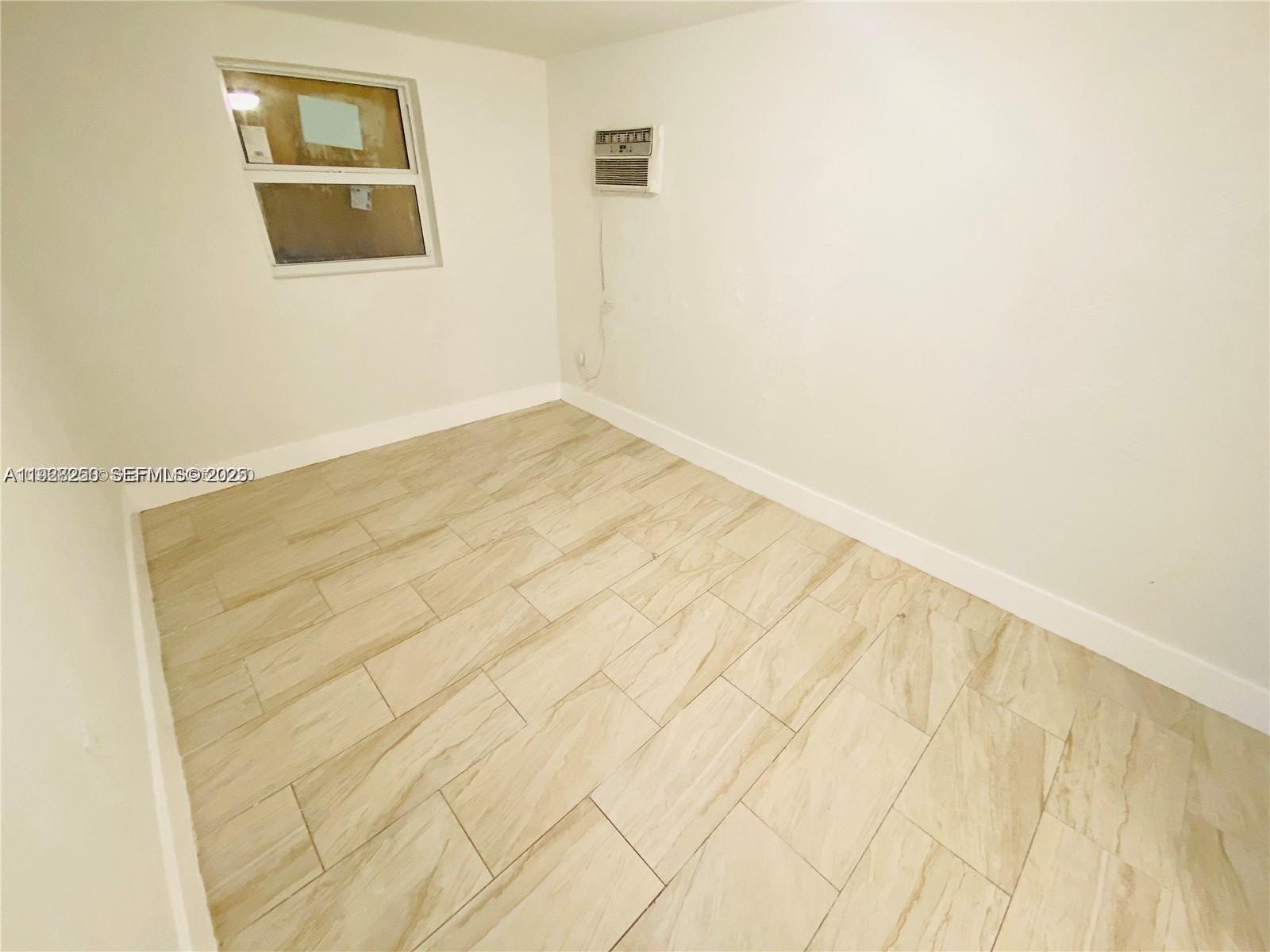 2230 Northwest 51st Terrace, Unit 2 Miami, FL 33142 - Photo 5 of 10 a view of a room with wooden floor and brick wall