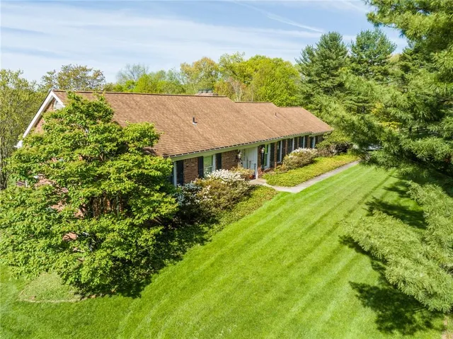 a view of a house with a big yard plants and large trees