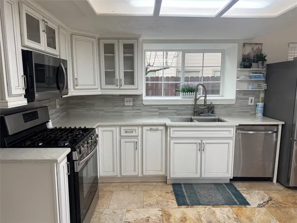 a kitchen with stainless steel appliances granite countertop a stove a sink and a microwave