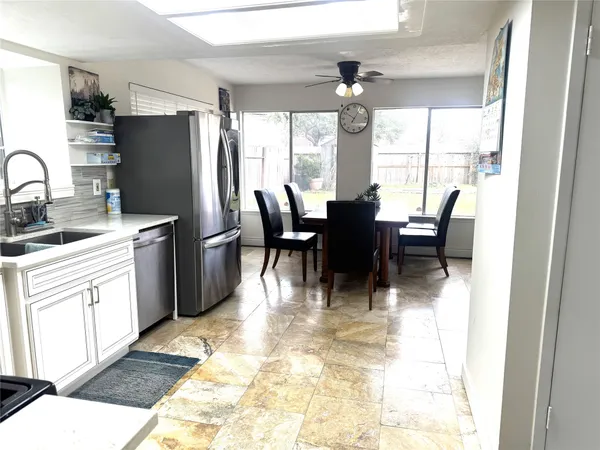 a dining room with stainless steel appliances granite countertop a dining table chairs and a refrigerator