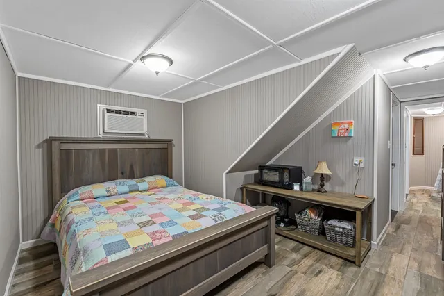 a bedroom with a bed and a dresser with wooden floor