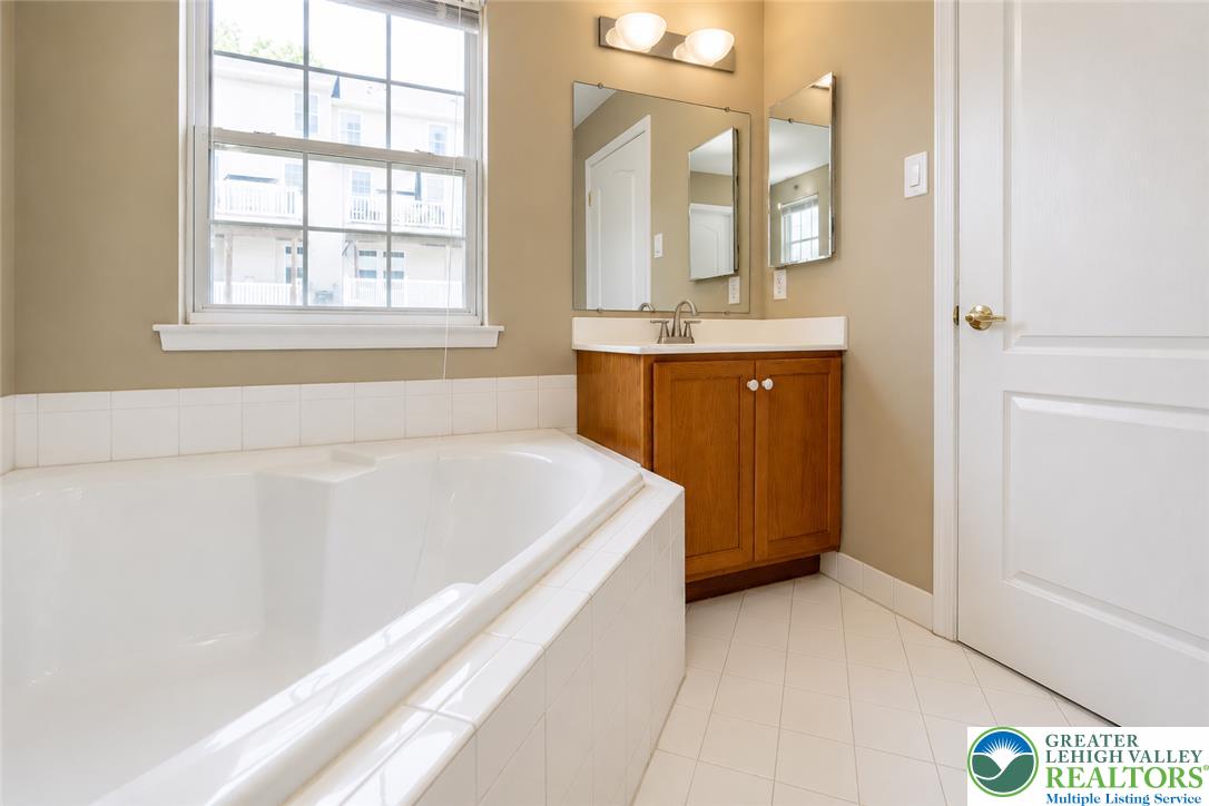 3566 Penfield Way Nazareth, PA 18064 - Photo 43 of 47 Relax in the deep soaking tub of this naturally illuminated bathroom, featuring a practical vanity and clean tile flooring.