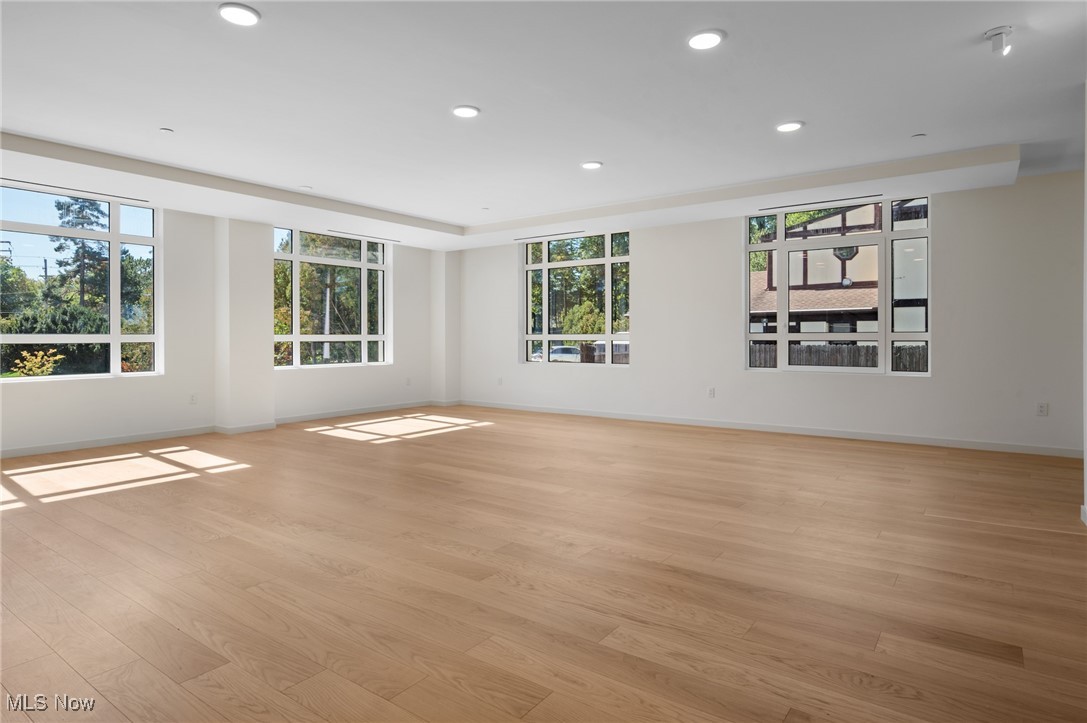 22700 Lake Road, Unit 306 Rocky River, OH 44116 - Photo 5 of 28 Empty room with light wood-style flooring, recessed lighting, and a tray ceiling