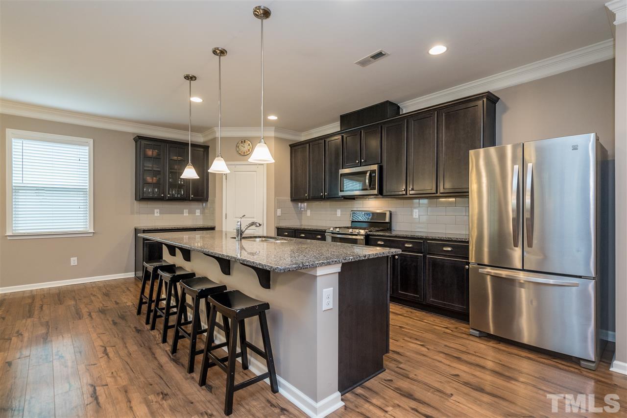 439 Plainview Avenue Raleigh, NC 27604 - Photo 5 of 29 a kitchen with stainless steel appliances granite countertop a refrigerator a stove top oven a sink dishwasher and a dining table with wooden floor