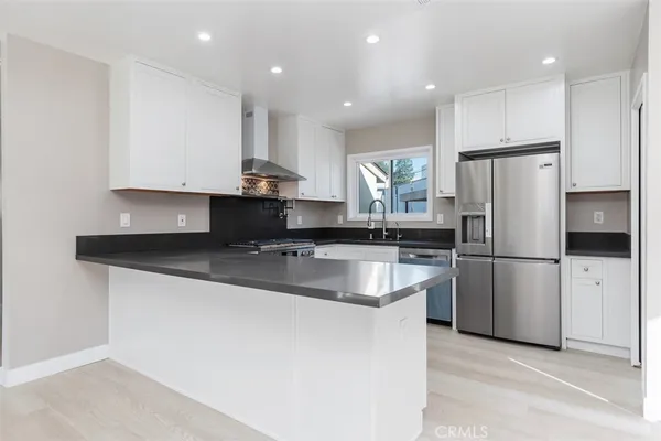 a kitchen with stainless steel appliances granite countertop a sink a stove a refrigerator and white cabinets