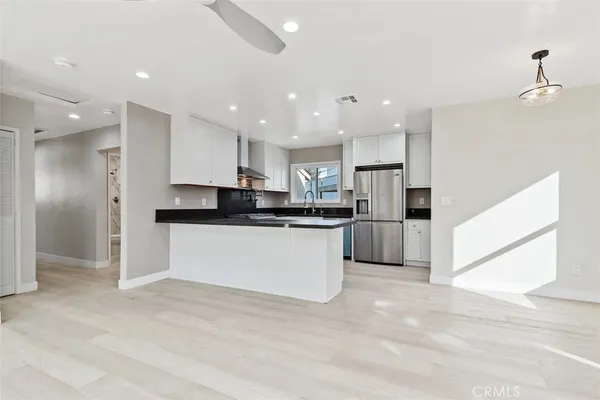 a large white kitchen with kitchen island a sink a center island stainless steel appliances and a cabinets