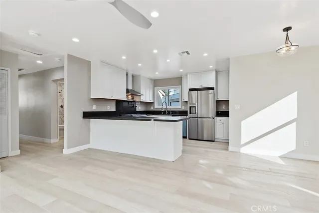 a large white kitchen with kitchen island a sink a center island stainless steel appliances and a cabinets