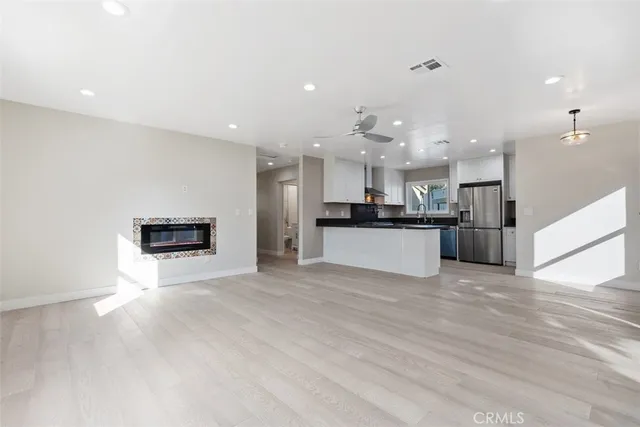 a view of kitchen with kitchen island granite countertop a stove top oven a sink and a refrigerator with wooden floor