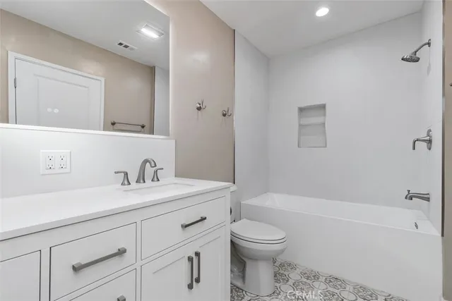 a bathroom with a toilet a sink a mirror a bathtub and vanity