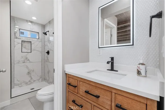 a bathroom with a granite countertop sink a toilet and shower