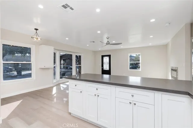 a large white kitchen with center island and stainless steel appliances