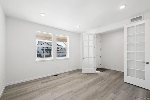 an empty room with wooden floor and windows