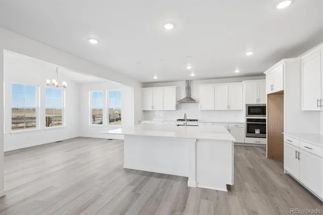 a kitchen with stainless steel appliances a sink a stove a refrigerator cabinets and a wooden floor