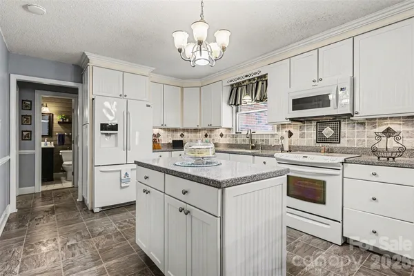 a kitchen with kitchen island granite countertop a sink cabinets stainless steel appliances and a center island
