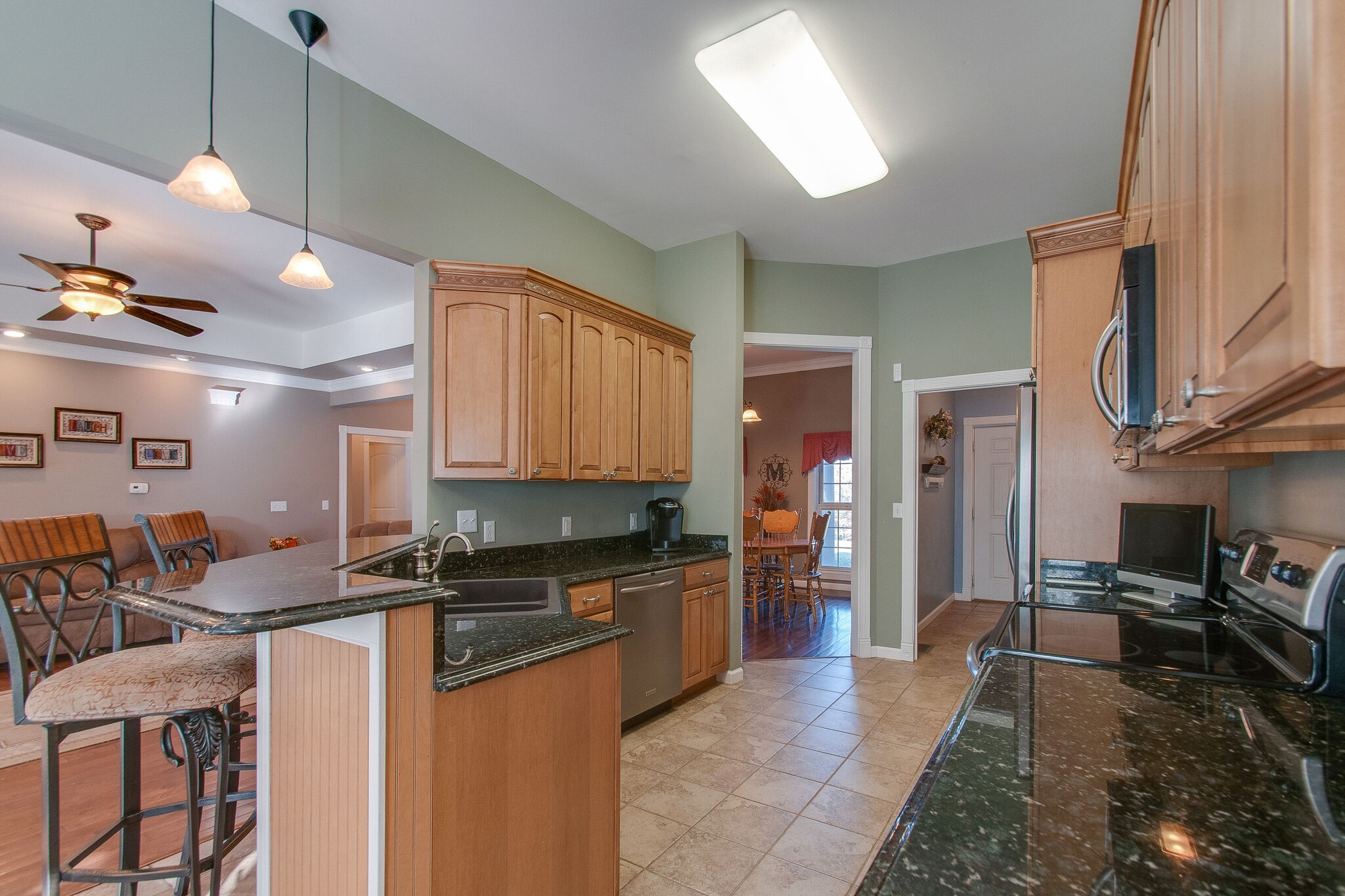 1230 Grindstone Hollow Road Dickson, TN 37055 - Photo 16 of 50 a kitchen with stainless steel appliances granite countertop a stove a sink a refrigerator white cabinets a dining table and chairs with wooden floor