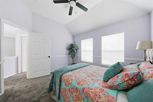 a bedroom with a bed a window and potted plant on the dresser