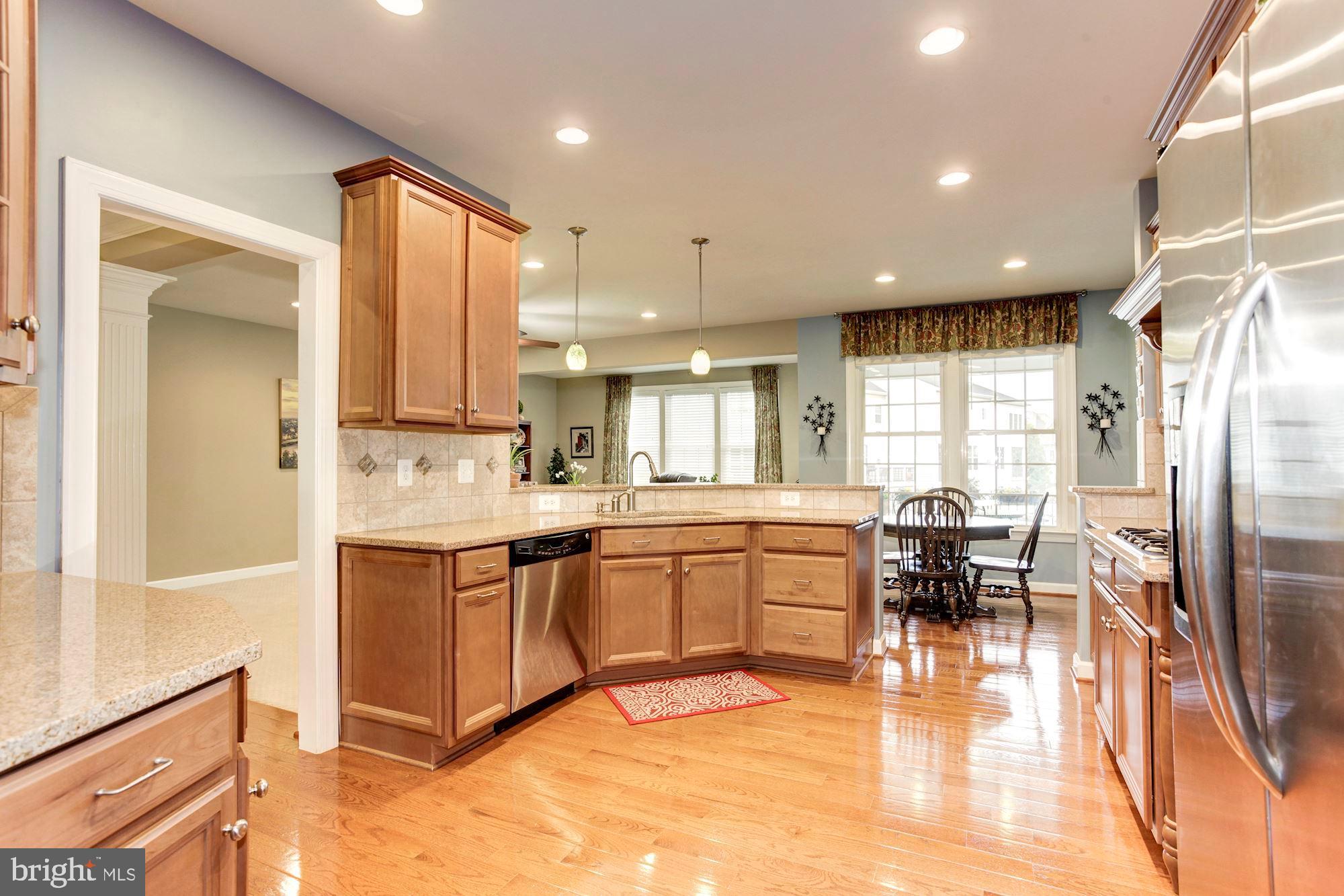 24960 Castleton Drive Chantilly, VA 20152 - Photo 5 of 44 a kitchen with stainless steel appliances granite countertop a refrigerator a sink a stove and white cabinets with wooden floor