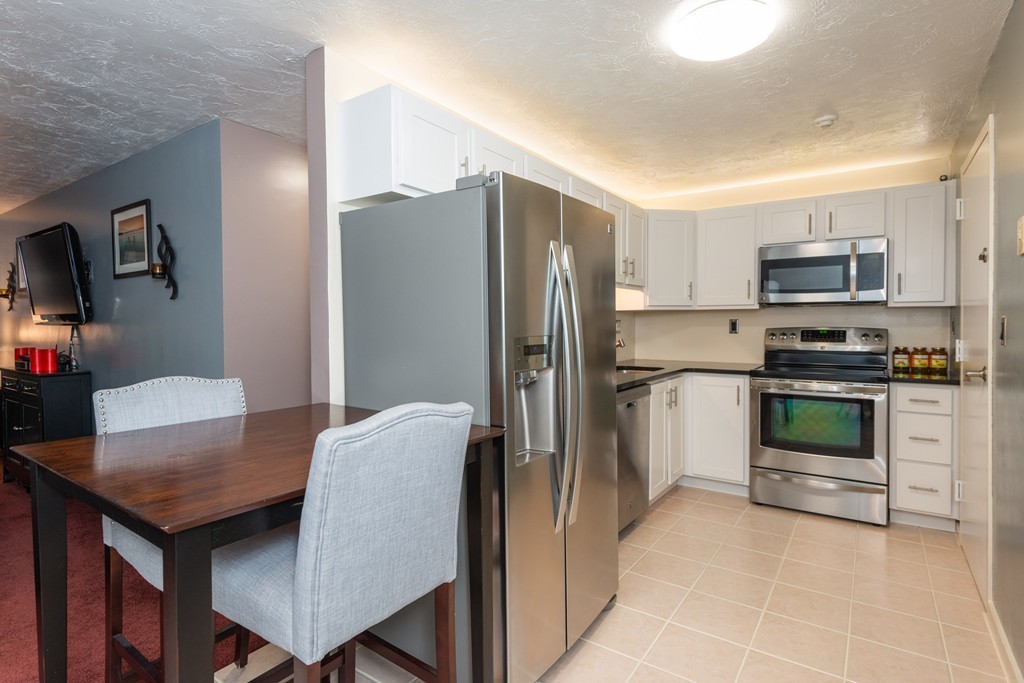 189 Littleton Road, Unit 19 Chelmsford, MA 01824 - Photo 6 of 42 a kitchen with stainless steel appliances a stove a refrigerator a sink a dining table and chairs