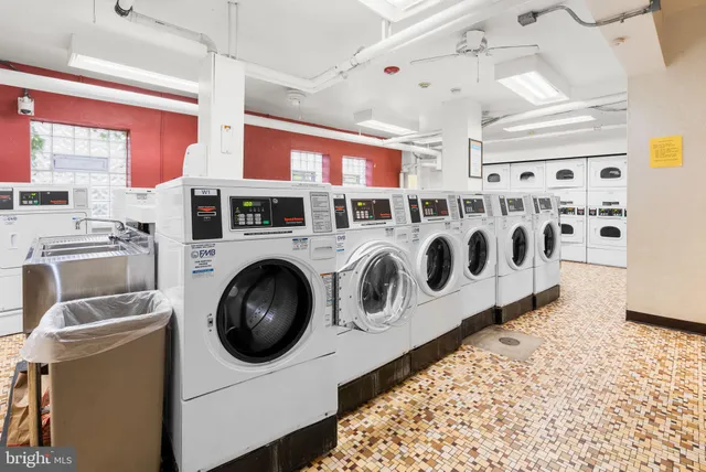 a utility room with stainless steel appliances wooden cabinets washer and dryer