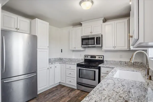 a kitchen with granite countertop a refrigerator stove and microwave