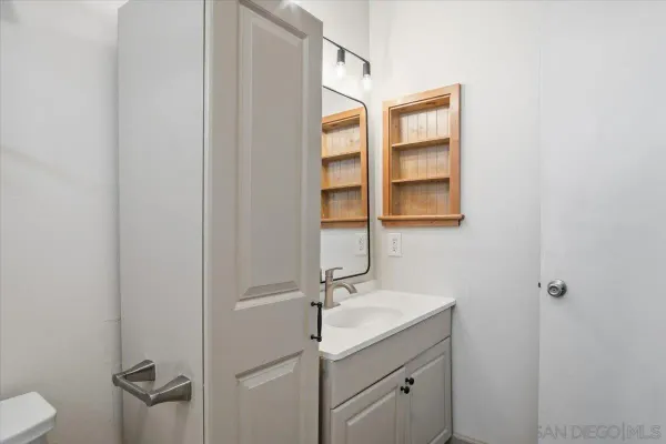 a bathroom with a granite countertop sink toilet and a window