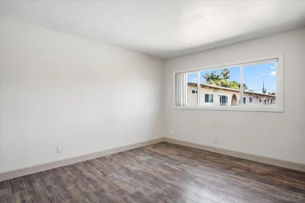 a view of empty room with wooden floor and window