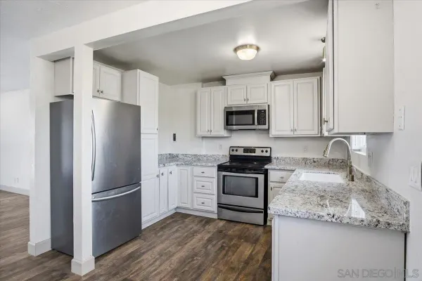 a kitchen with granite countertop a refrigerator stove and sink
