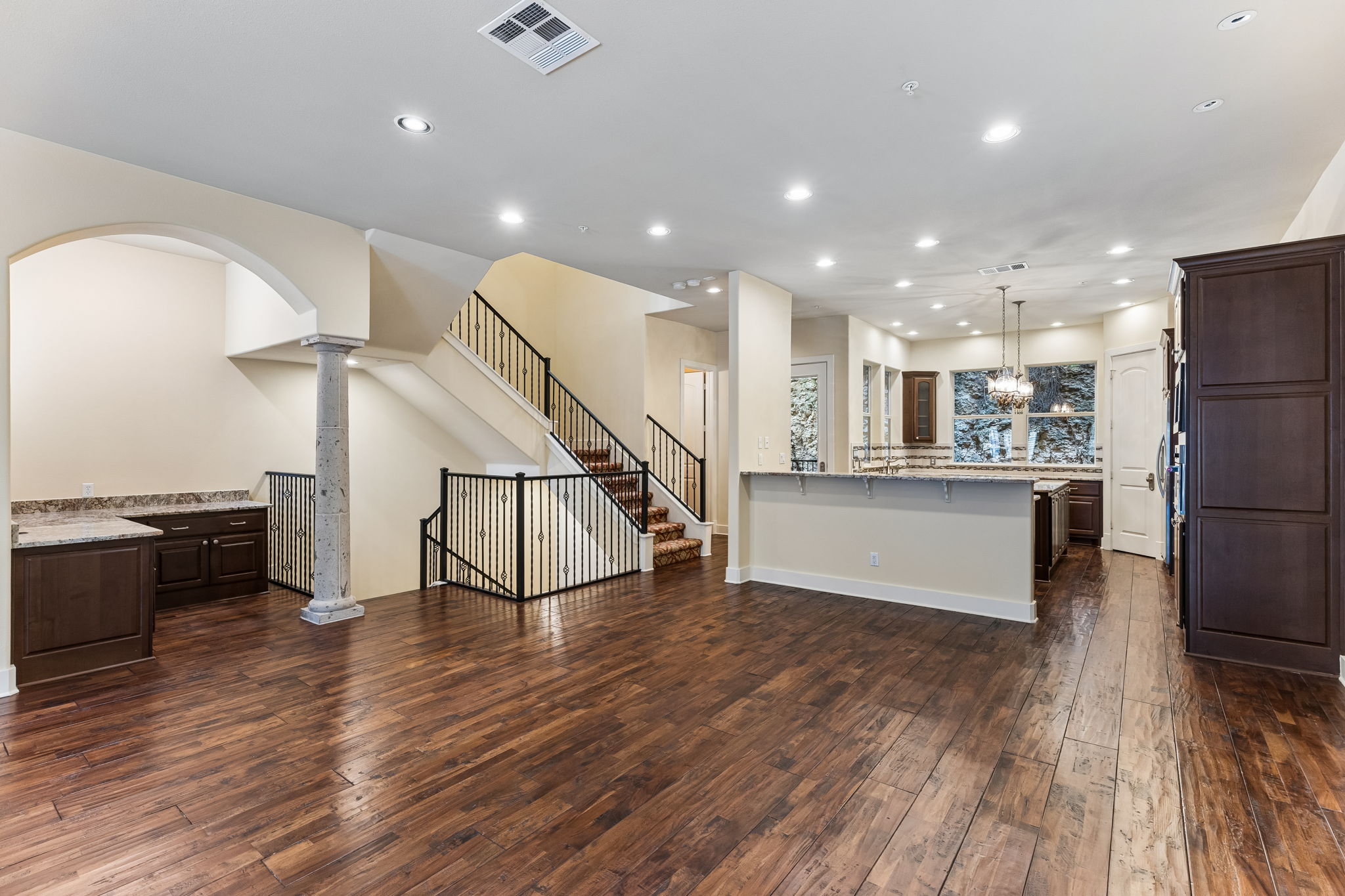 1529 Barton Springs Road, Unit 9 Austin, TX 78704 - Photo 12 of 37 Expansive open concept living area featuring dark wood flooring, recessed lighting, a staircase with wrought iron balusters, and a kitchen with dark cabinetry and a large window