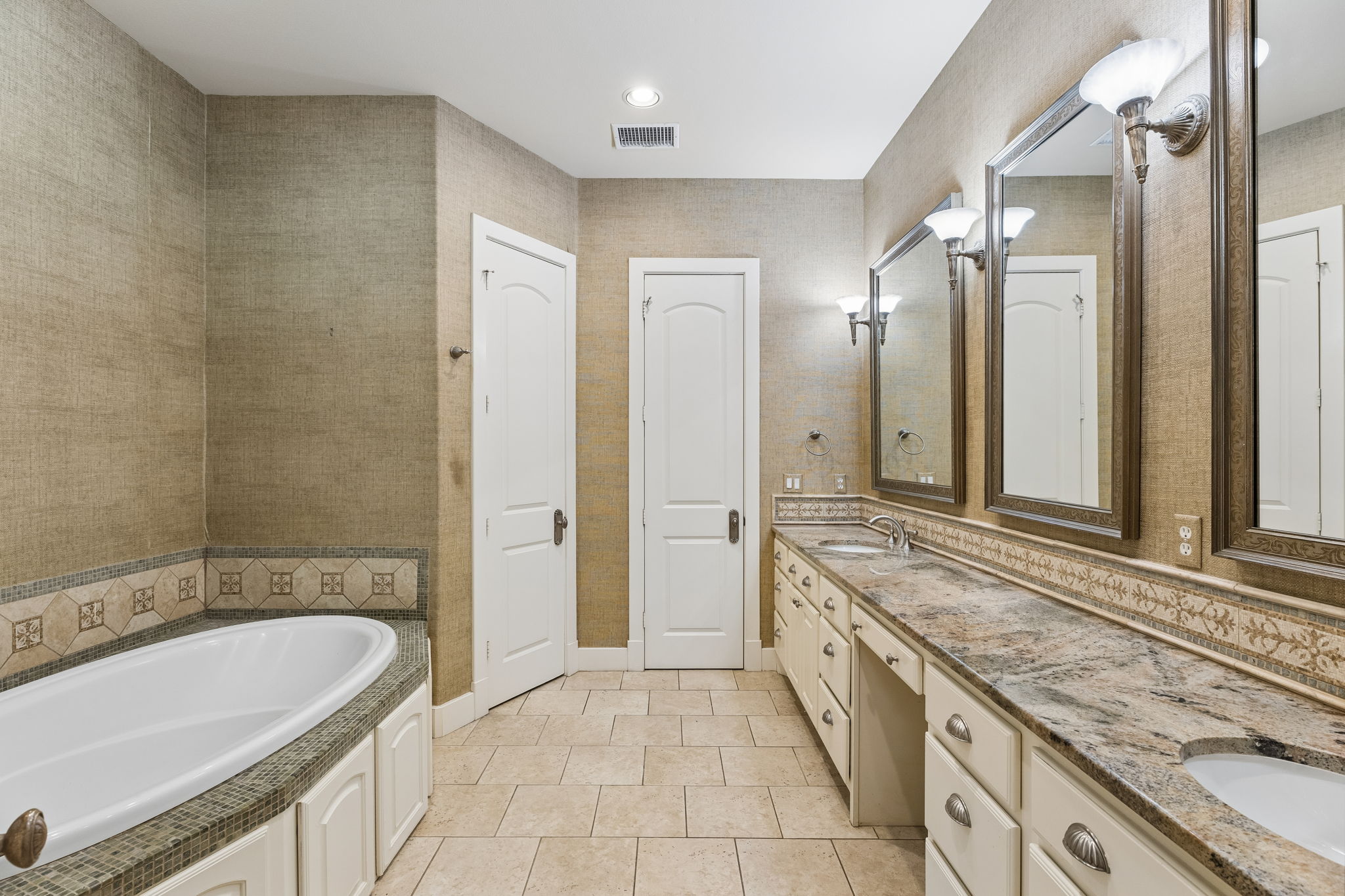 1529 Barton Springs Road, Unit 9 Austin, TX 78704 - Photo 33 of 37 This bathroom features a large soaking tub with decorative tile surround, a spacious vanity with dual sinks, and two framed mirrors with sconce lighting