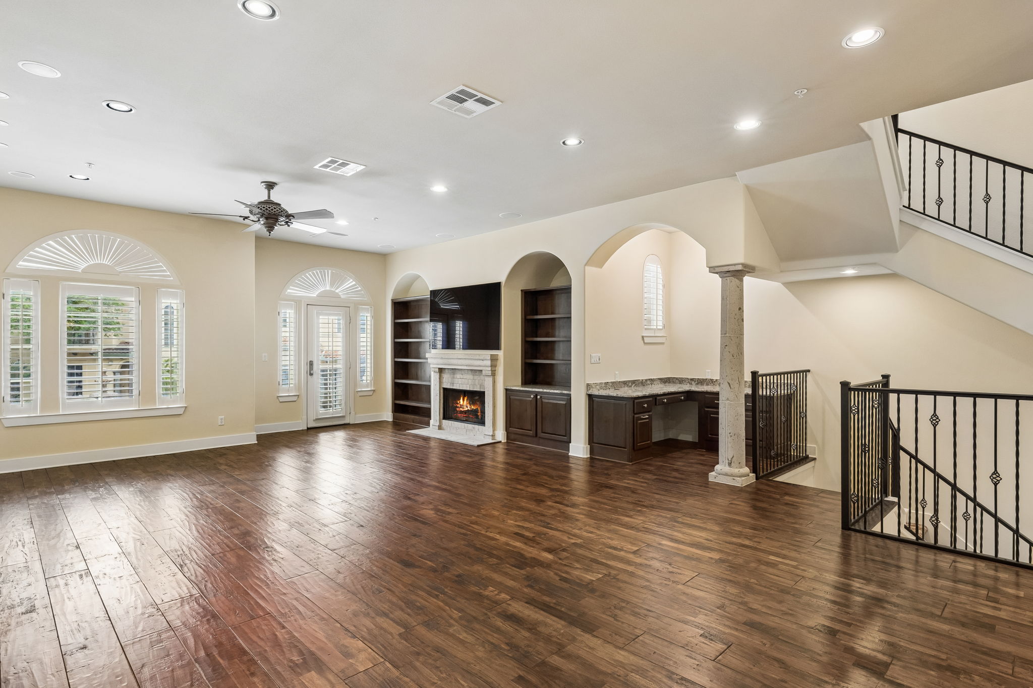 1529 Barton Springs Road, Unit 9 Austin, TX 78704 - Photo 10 of 37 Open concept living space featuring hardwood floors, a fireplace with a stone surround, and arched windows with plantation shutters