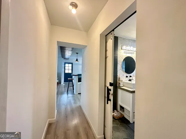 a view of a hallway with wooden floor and living room
