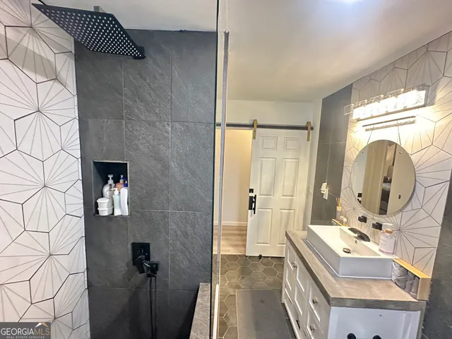a bathroom with a sink and mirror with bathtub