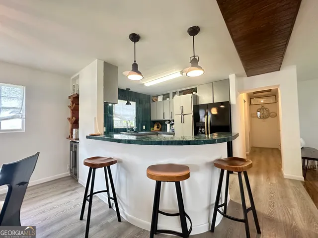 a kitchen with stainless steel appliances granite countertop white cabinets and chairs