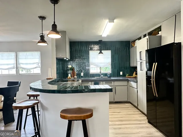 a kitchen with stainless steel appliances granite countertop a refrigerator a sink a stove a dining table and chairs