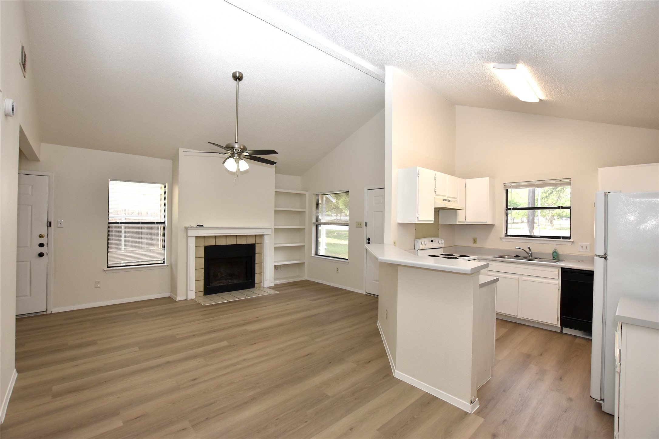 2801 West Slaughter Lane, Unit A Austin, TX 78748 - Photo 4 of 15 a view of a kitchen with a sink a kitchen island wooden floor and a fireplace