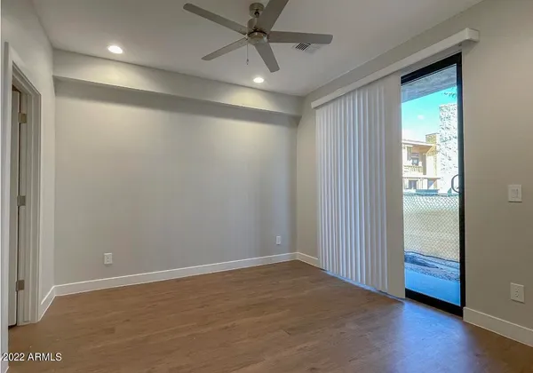 an empty room with wooden floor and a ceiling fan