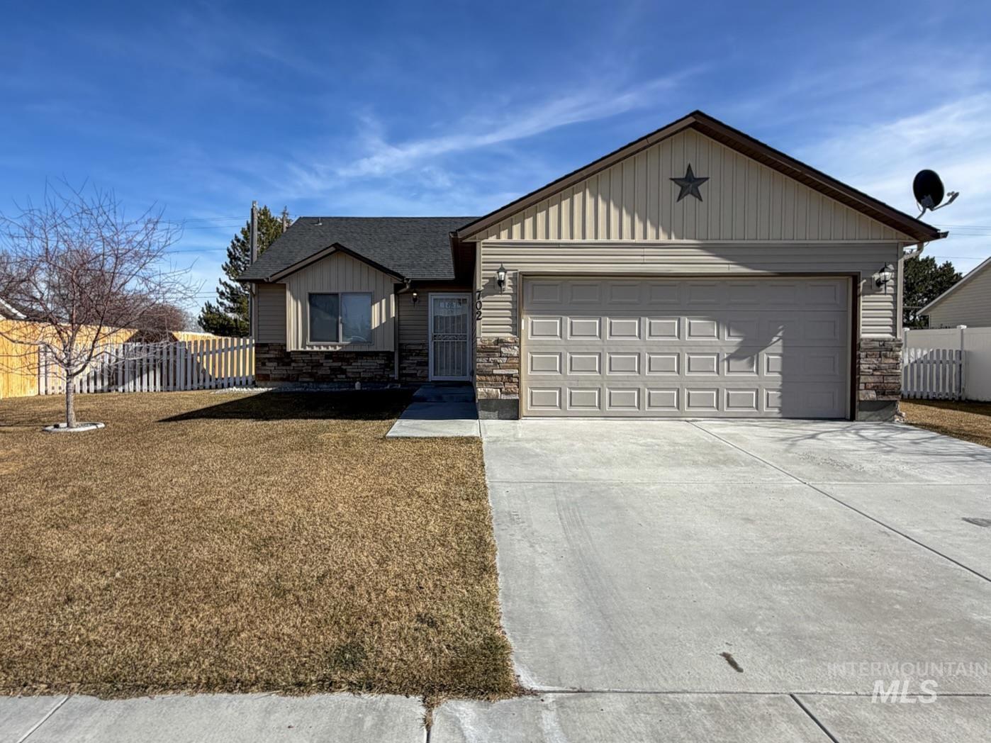 Single story home with driveway, board and batten siding, an attached garage, and stone siding