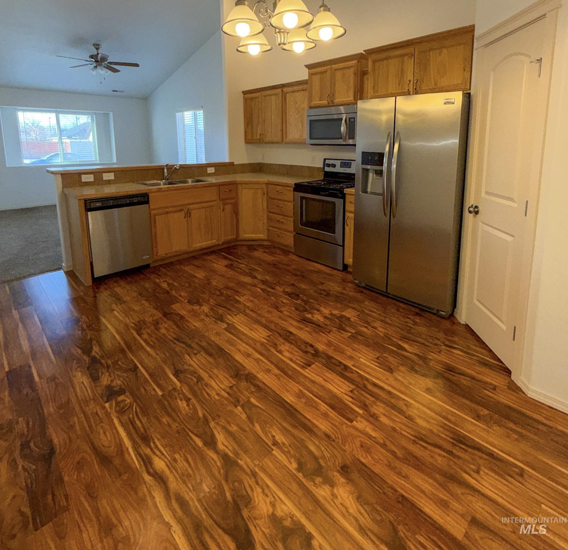 702 Emerald Street Rupert, ID 83350 - Photo 6 of 12 Kitchen featuring stainless steel appliances, suspended lighting, a peninsula, lofted ceiling, and dark wood-style flooring