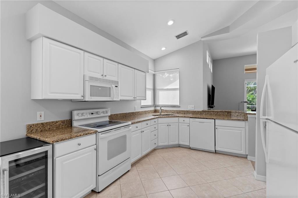 1717 Winding Oaks Way Naples, FL 34109 - Photo 12 of 29 a kitchen with granite countertop white cabinets and white appliances