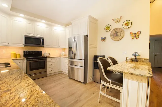 a kitchen with stainless steel appliances granite countertop a stove top oven a refrigerator a sink with a dining table and chairs