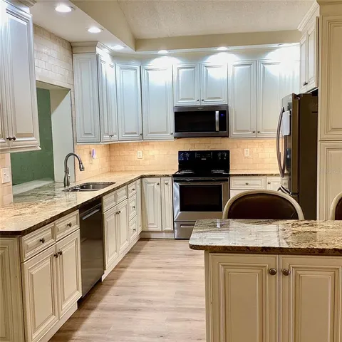 a kitchen with stainless steel appliances granite countertop a sink stove and refrigerator