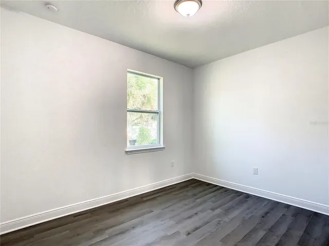 an empty room with wooden floor closet and windows