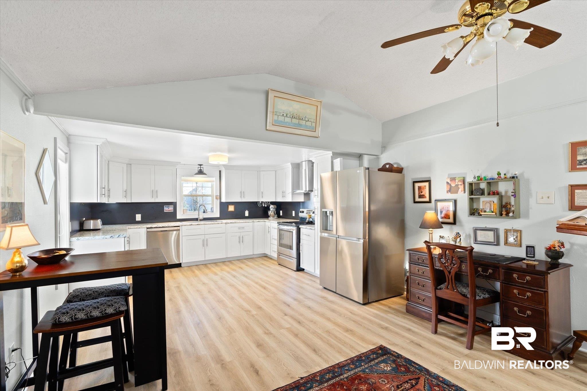 14280 Cat Deakle Road Grand Bay, AL 36541 - Photo 10 of 51 Kitchen with light wood-style flooring, stainless steel appliances, wall chimney range hood, white cabinetry, and a sink