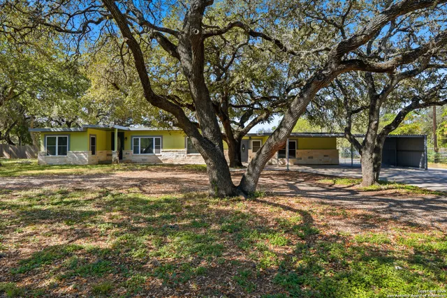 a backyard of a house with large trees and table