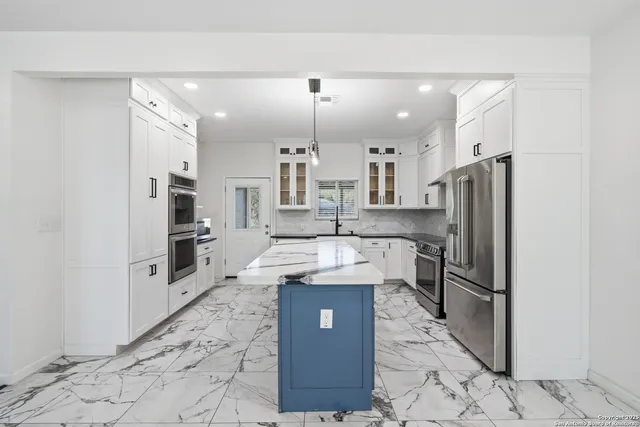 a large kitchen with granite countertop a large stove a sink dishwasher a refrigerator and cabinets